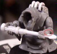 His thumb is circled red. I drilled a hole through his fist and then cut a gap between his knuckles to squeeze the screwdriver into.